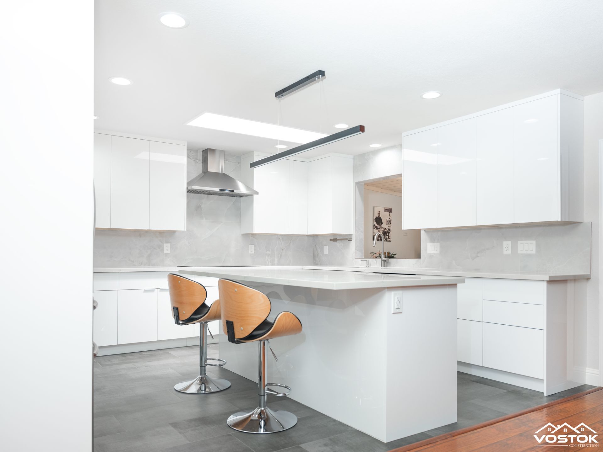 A kitchen with white cabinets , a large island , and two bar stools.