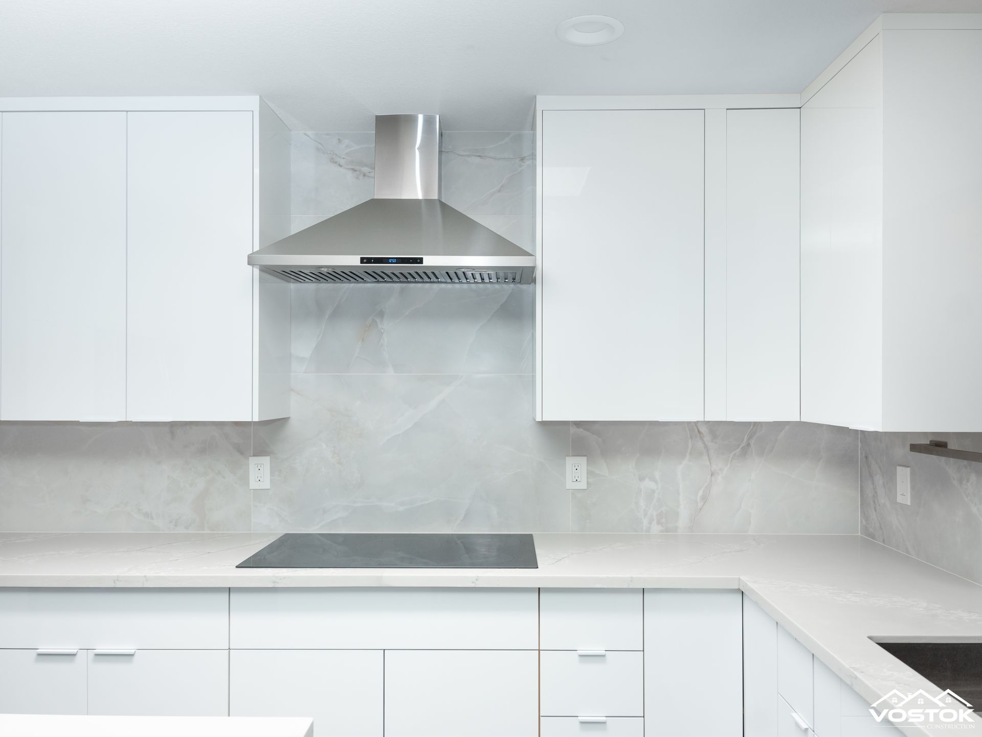 A kitchen with white cabinets and a stove top oven.
