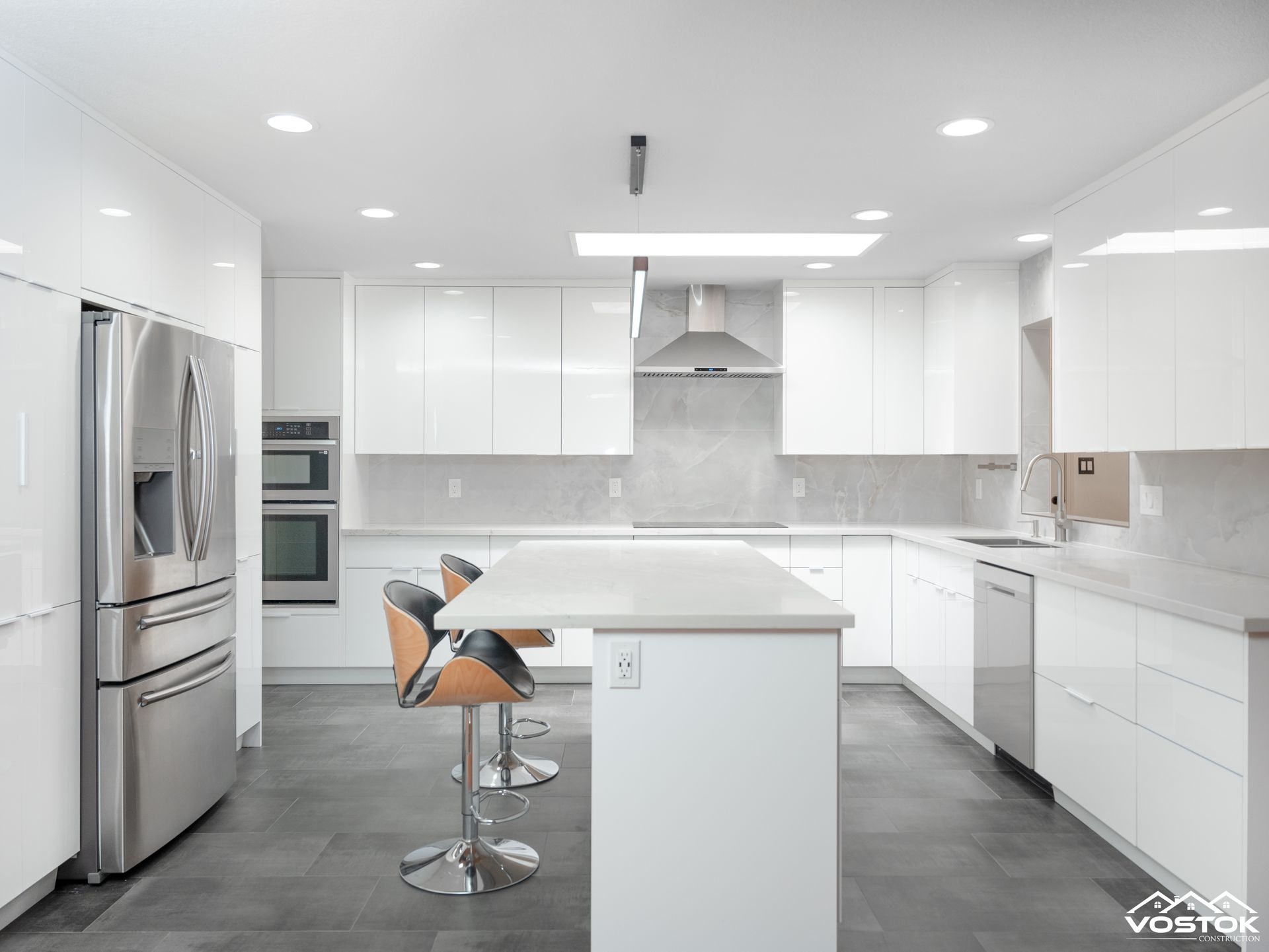 A kitchen with white cabinets , stainless steel appliances , and a large island.