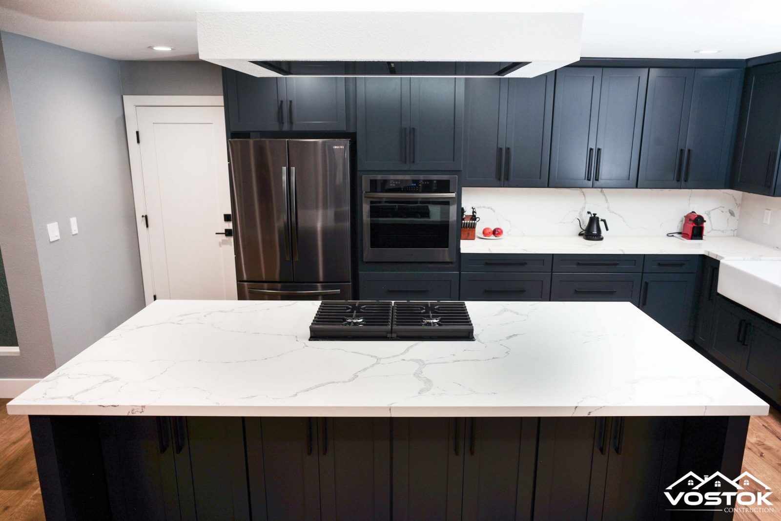 A kitchen with black cabinets and a large island in the middle.