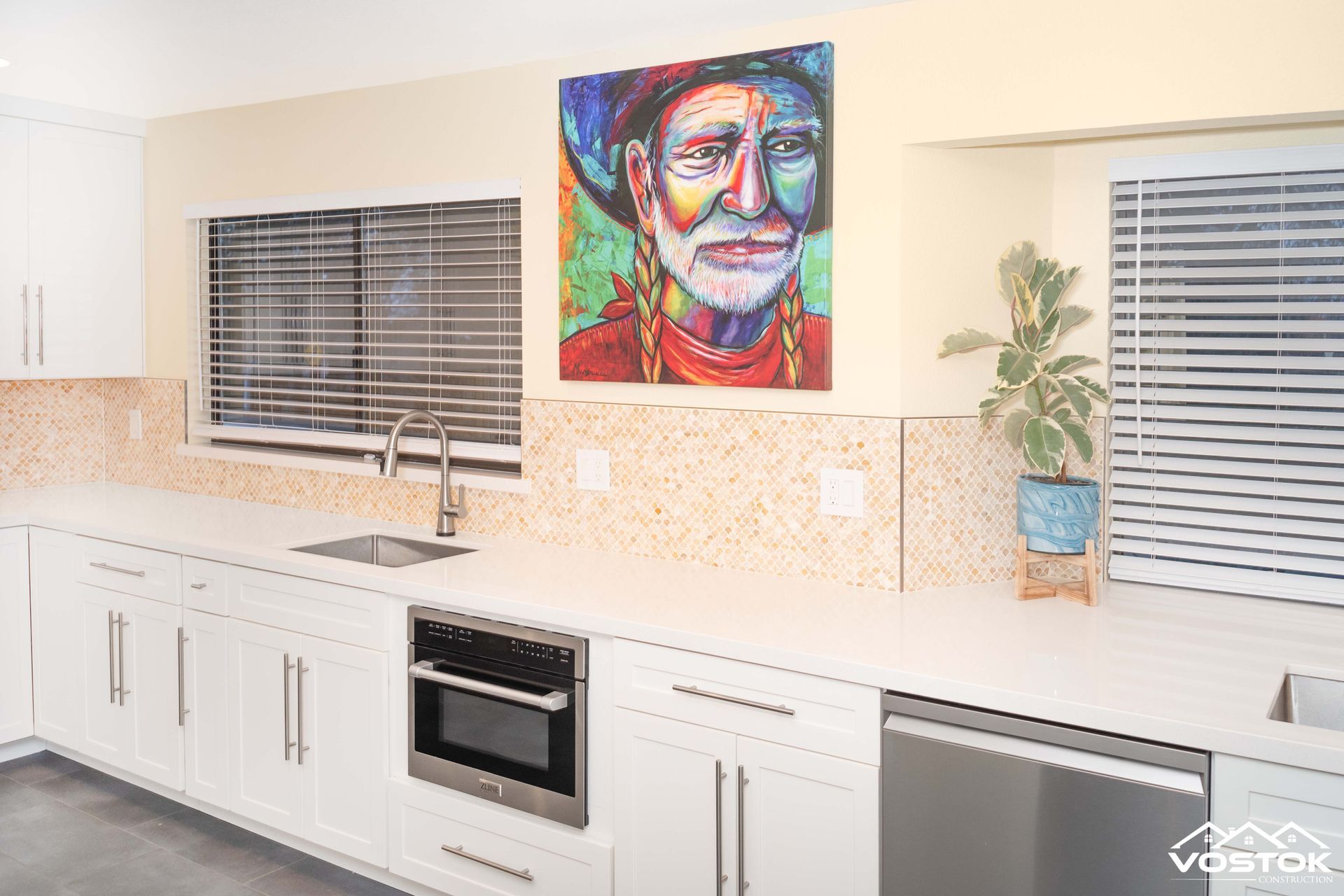 A kitchen with a painting of a man on the wall above the sink.