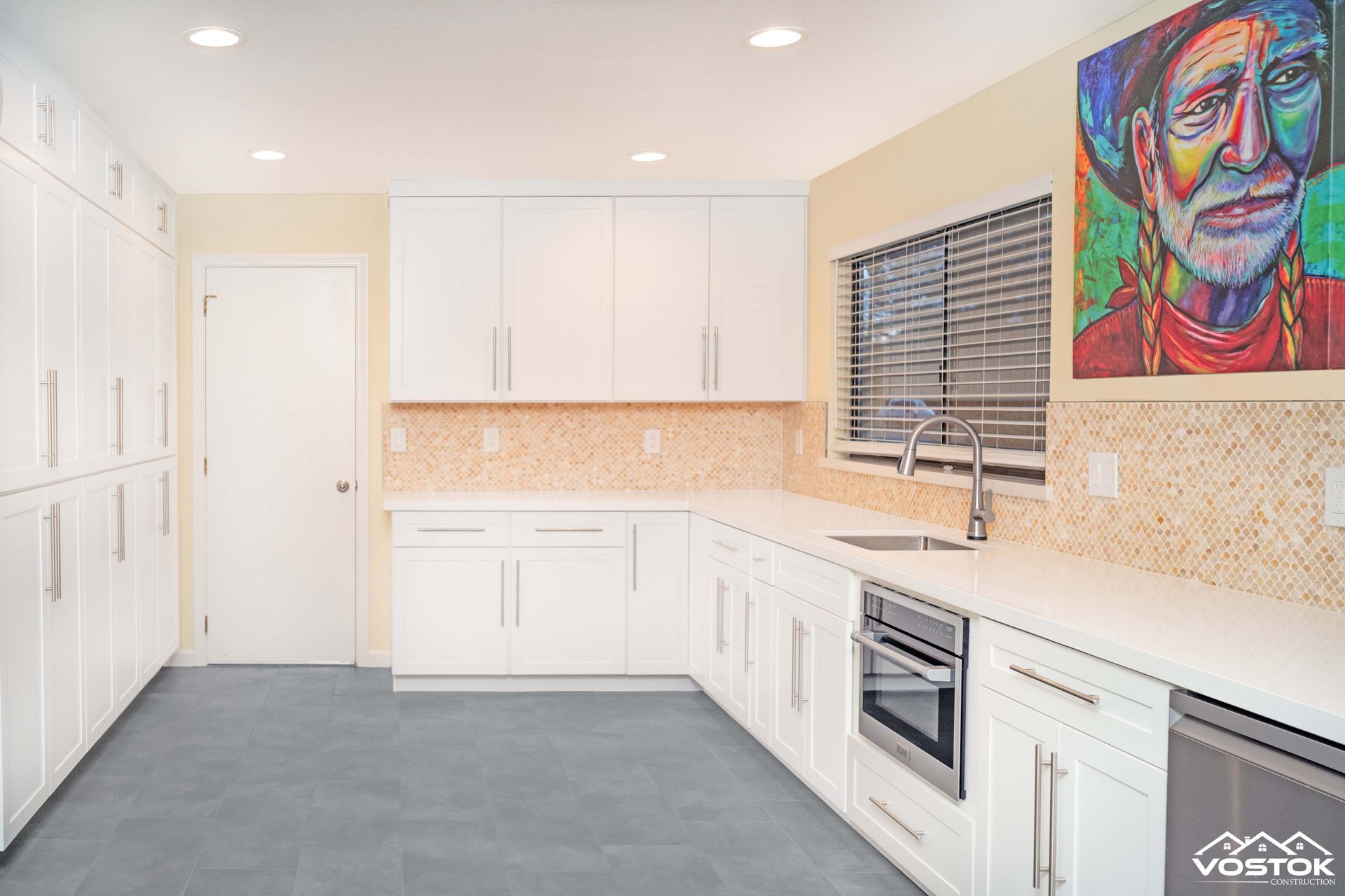 A kitchen with white cabinets and a painting on the wall.