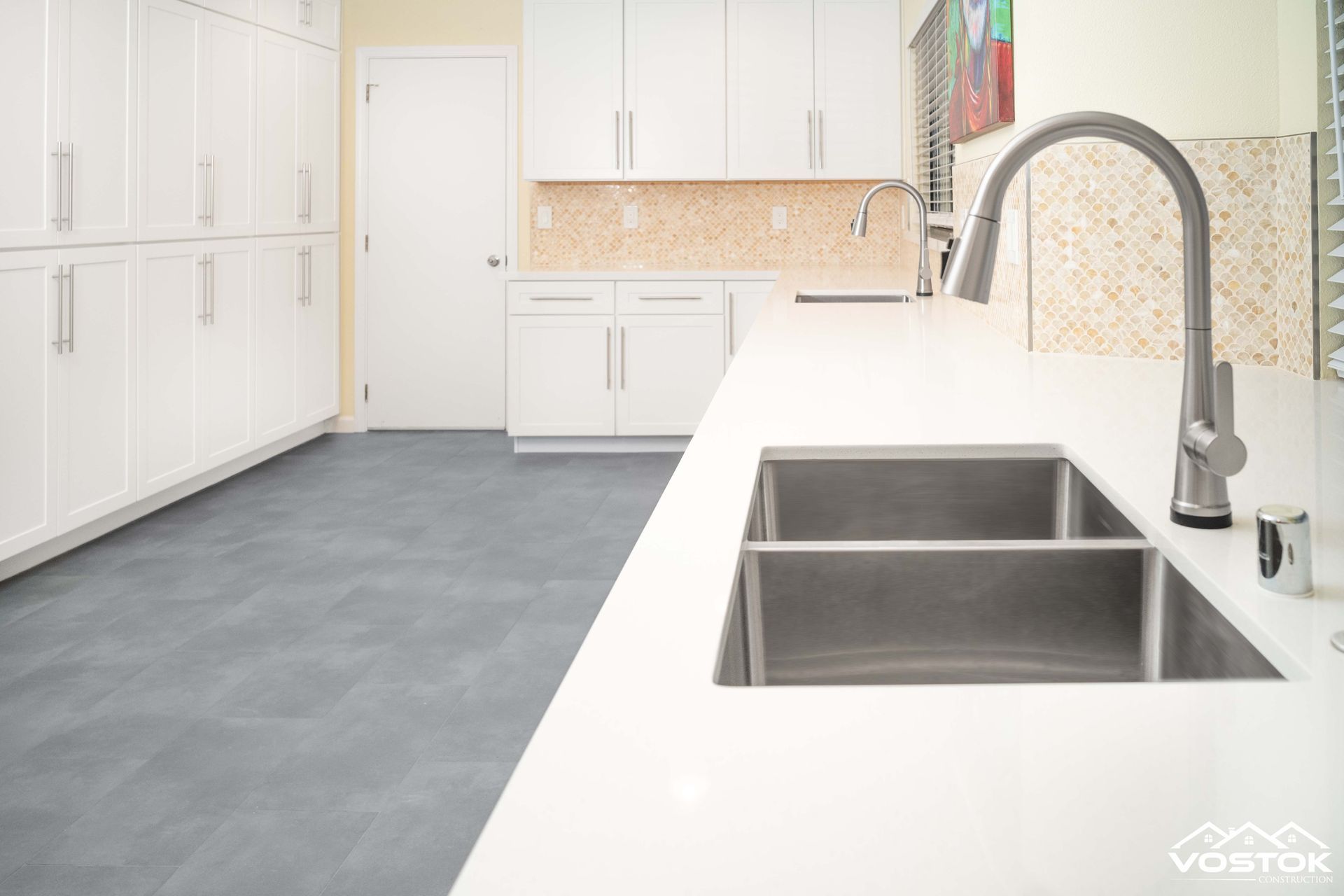 A kitchen with white cabinets and a stainless steel sink.