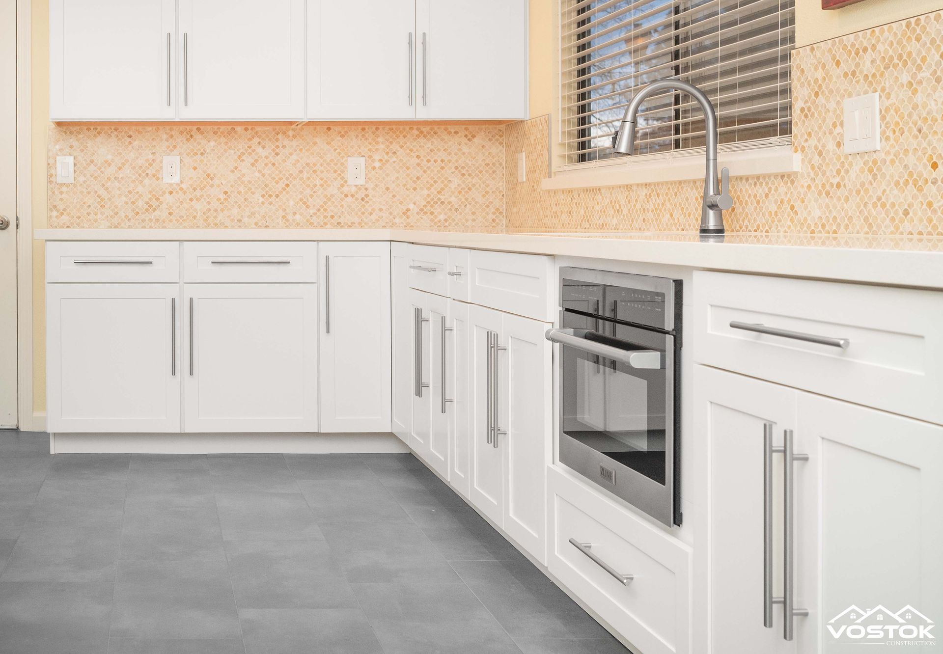 A kitchen with white cabinets , stainless steel appliances , a sink , and a window.