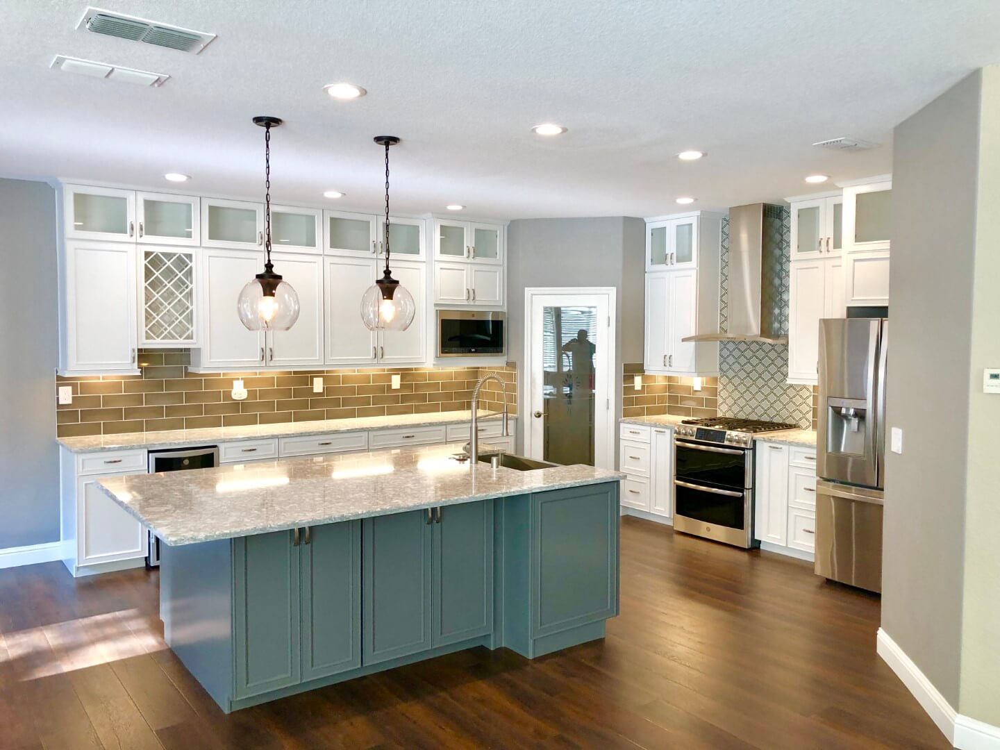 A kitchen with a large island in the middle and stainless steel appliances.