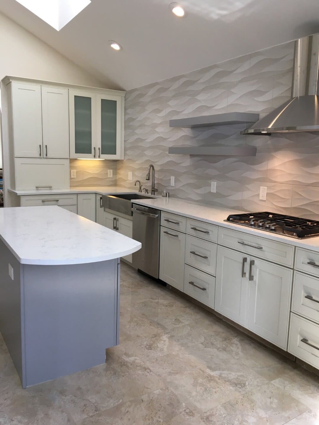 A kitchen with white cabinets , stainless steel appliances and a large island.