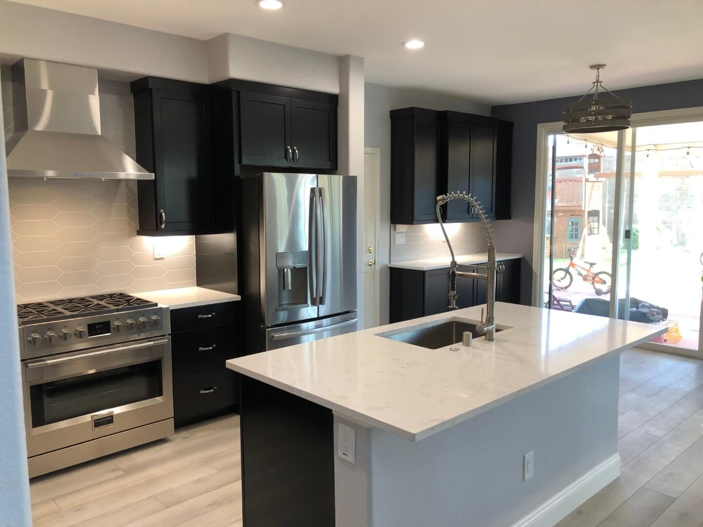 A kitchen with stainless steel appliances and black cabinets