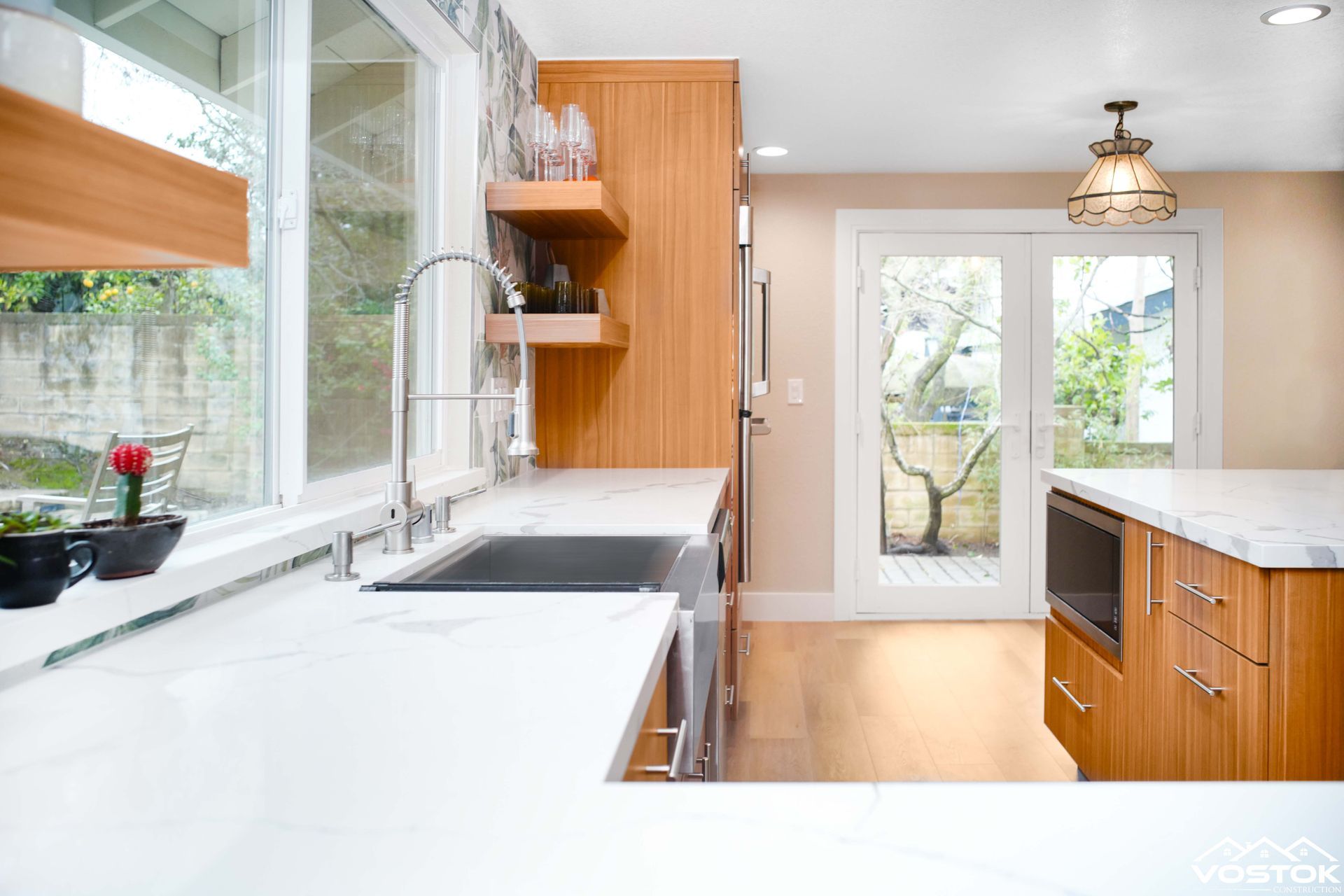 A kitchen with a sink , stainless steel appliances , wooden cabinets and white counter tops.