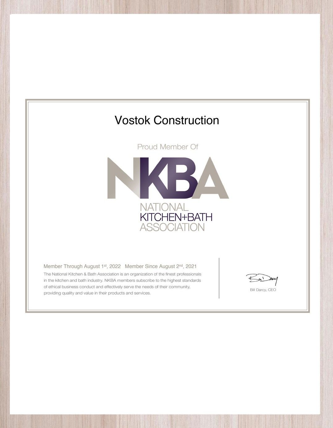 A certificate from the national kitchen bath association is sitting on a wooden table.