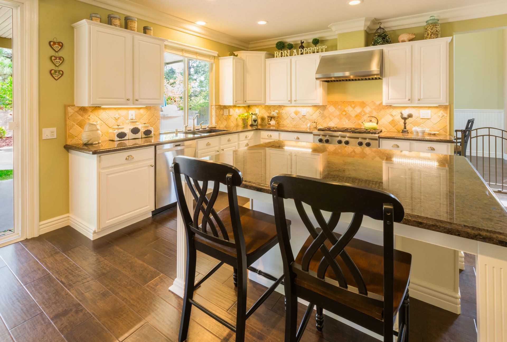 A beautiful kitchen with lit counters, green walls, and shiny countertops