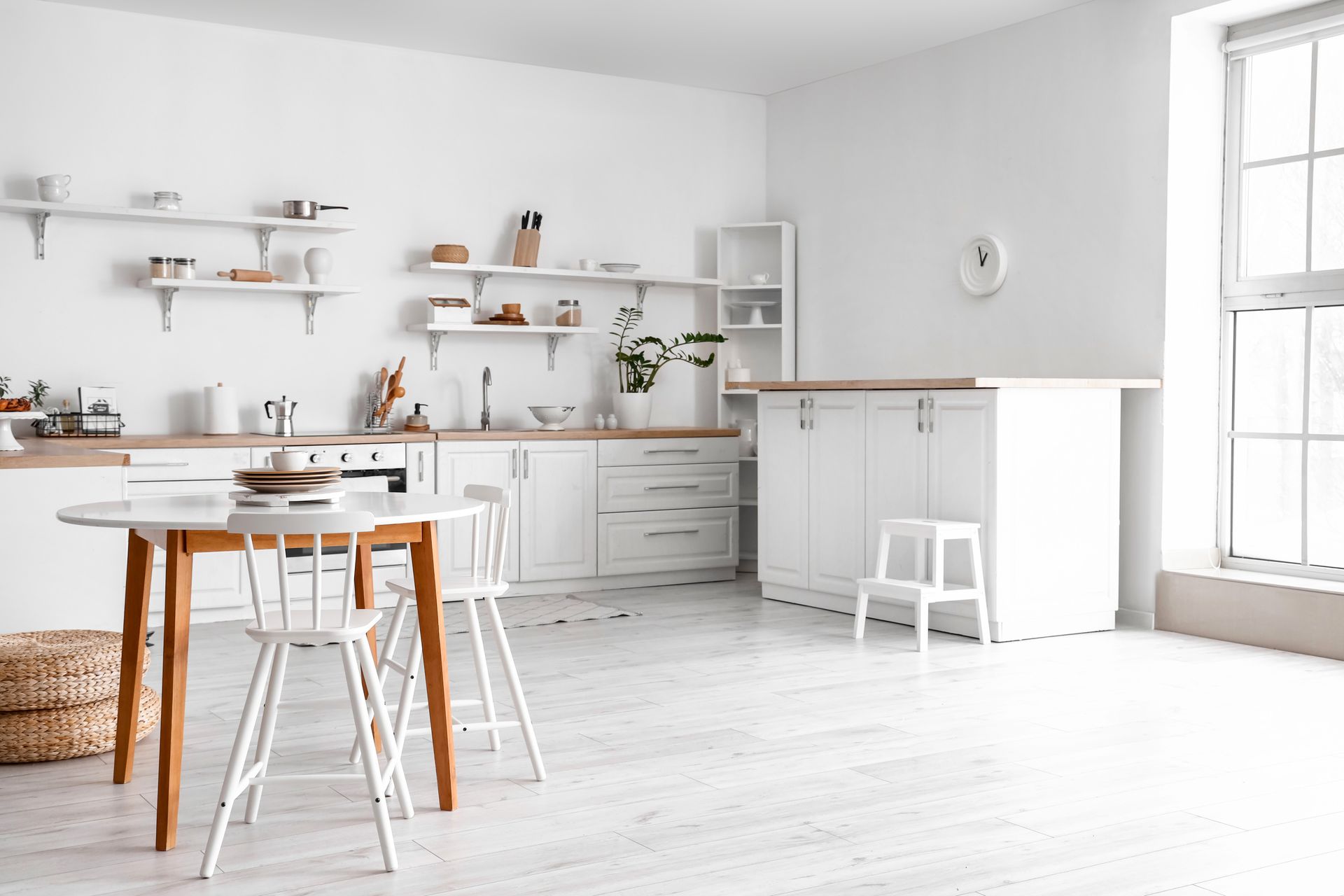 A minimalist kitchen with white and brown tables and counters 