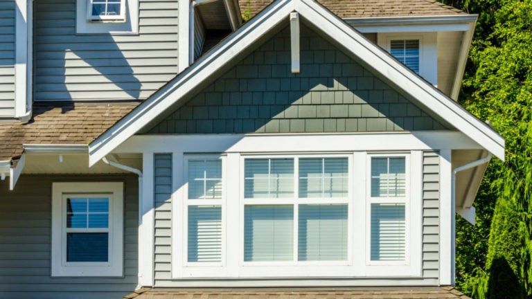 A house with a green siding and white trim has a lot of windows.