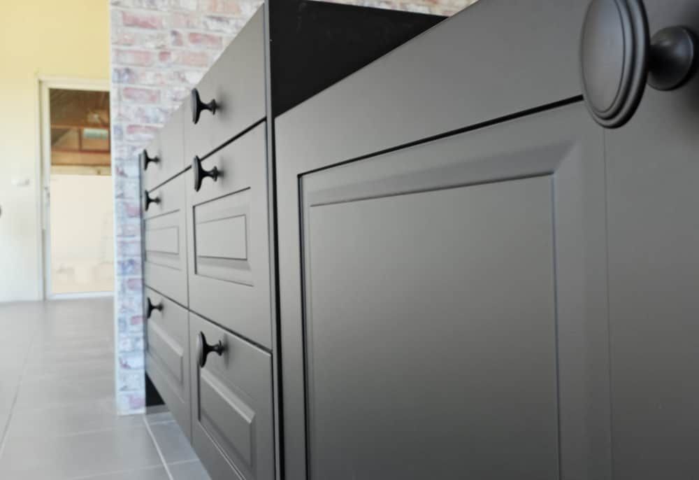 A Kitchen With Black Cabinets And Drawers And A Brick Wall — South East Kitchens In Burleigh Heads, QLD