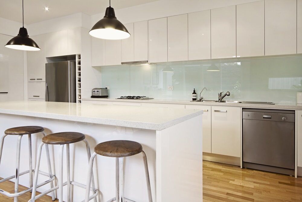 A Kitchen With White Cabinets, Stools, A Dishwasher And A Refrigerator — South East Kitchens In Gold Coast, QLD