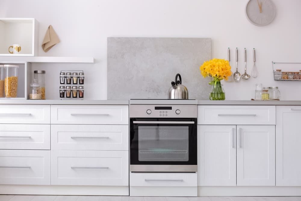A Kitchen With White Cabinets, Stainless Steel Appliances, And A Clock On The Wall — South East Kitchens In Burleigh Heads, QLD