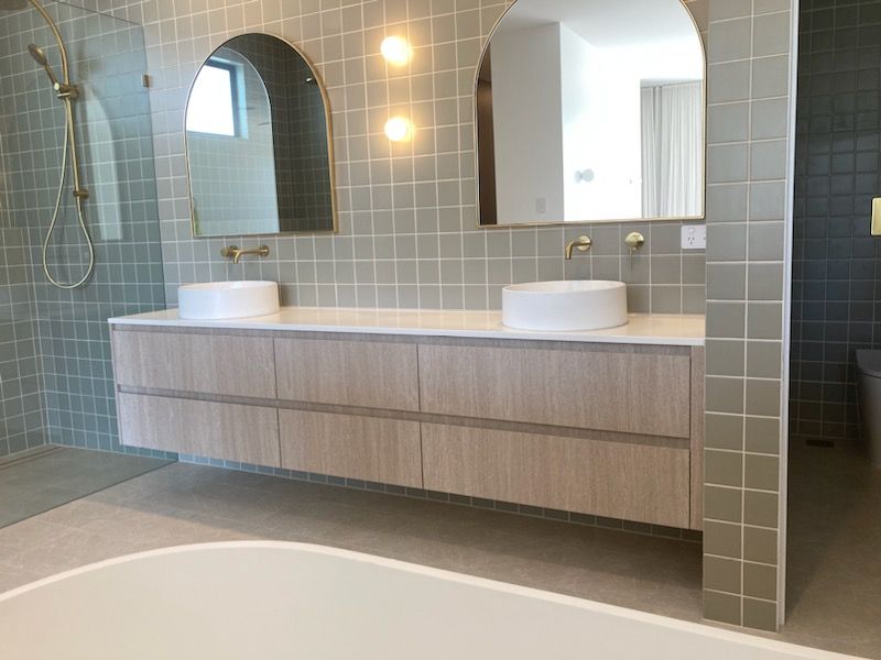 Bathroom With Green Tile Backdrop, Warm Pendant Lighting, Two Sinks, and Two Gold-framed Mirrors - South East Kitchens QLD Burleigh