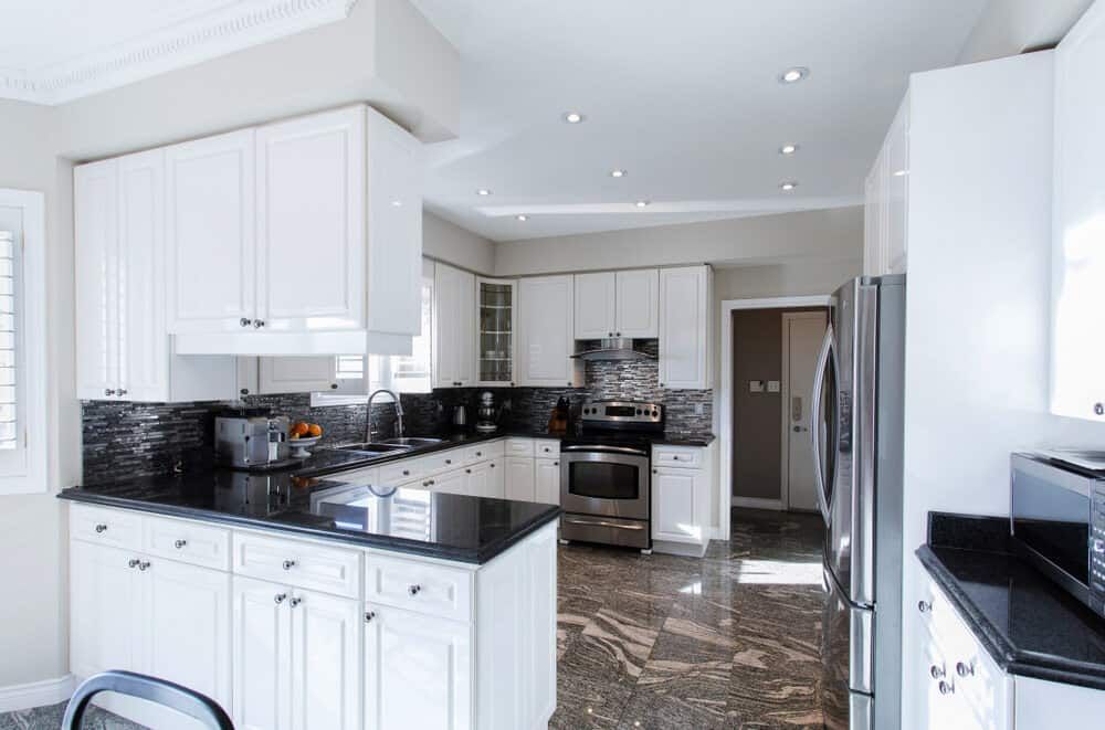 A Kitchen With White Cabinets, Black Counter Tops, And Steel Appliances — South East Kitchens In Burleigh Heads, QLD