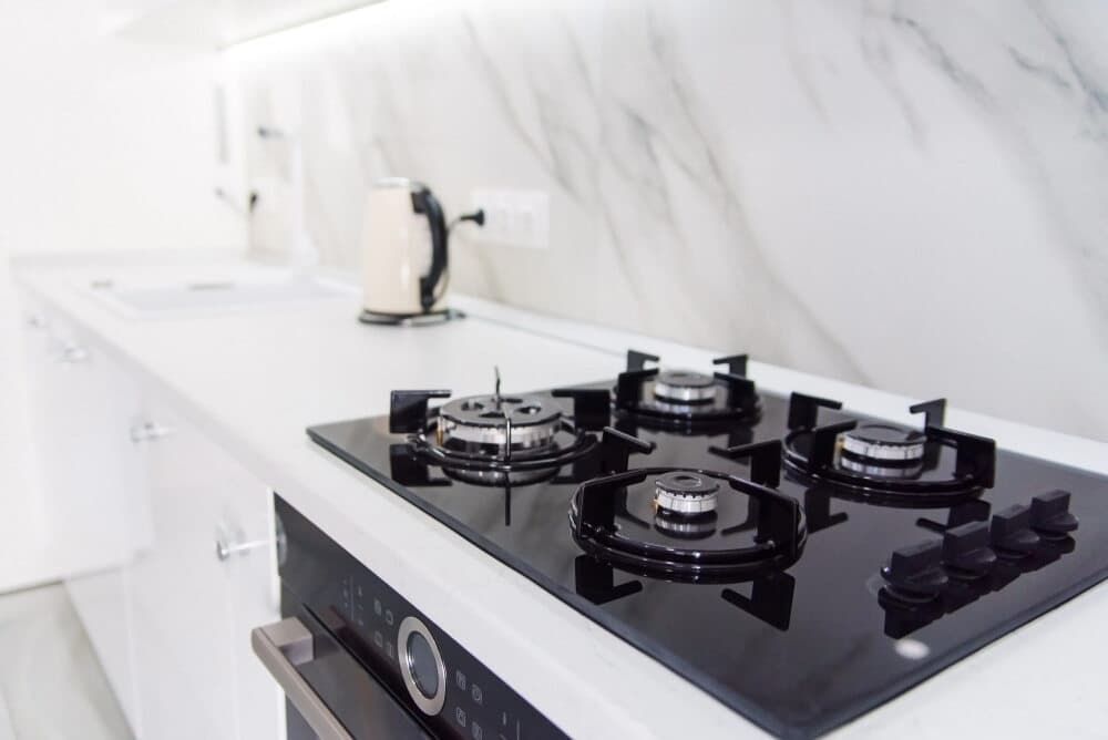 A Black Stove Top Oven Is Sitting On Top Of A White Counter In A Kitchen — South East Kitchens In Burleigh Heads, QLD