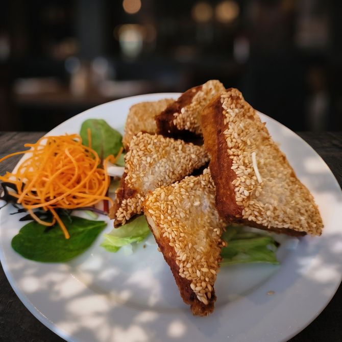 Dumplings in a white bowl with herbs and red sauce on a dark tabletop