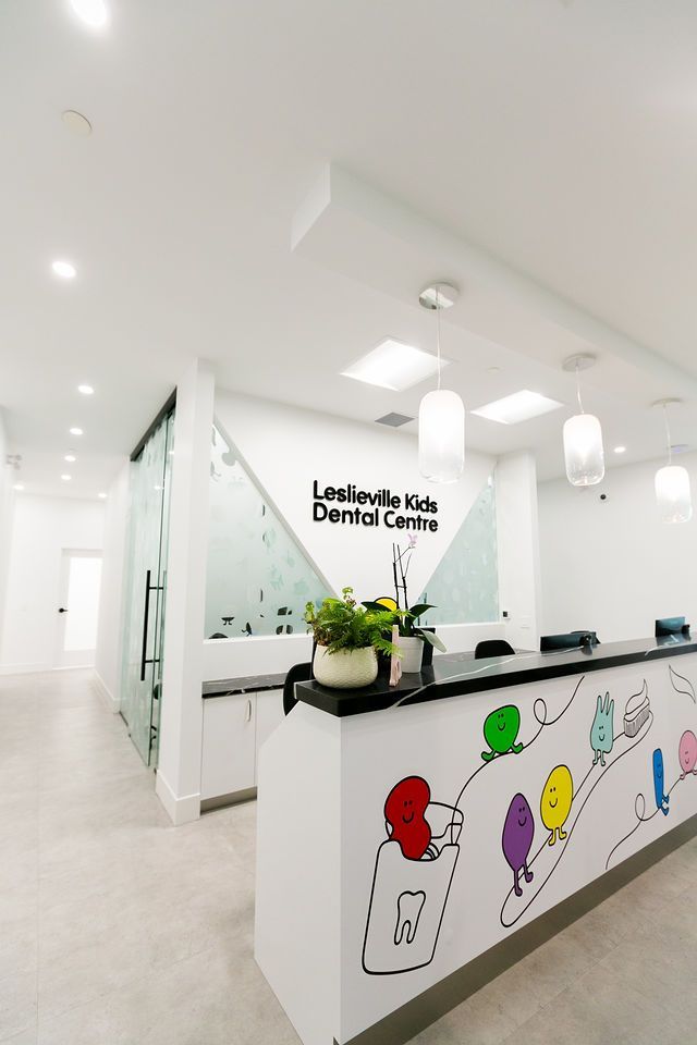 Modern reception desk at Leslieville Kids Dental Centre with colorful cartoon wall art and indoor plants.
