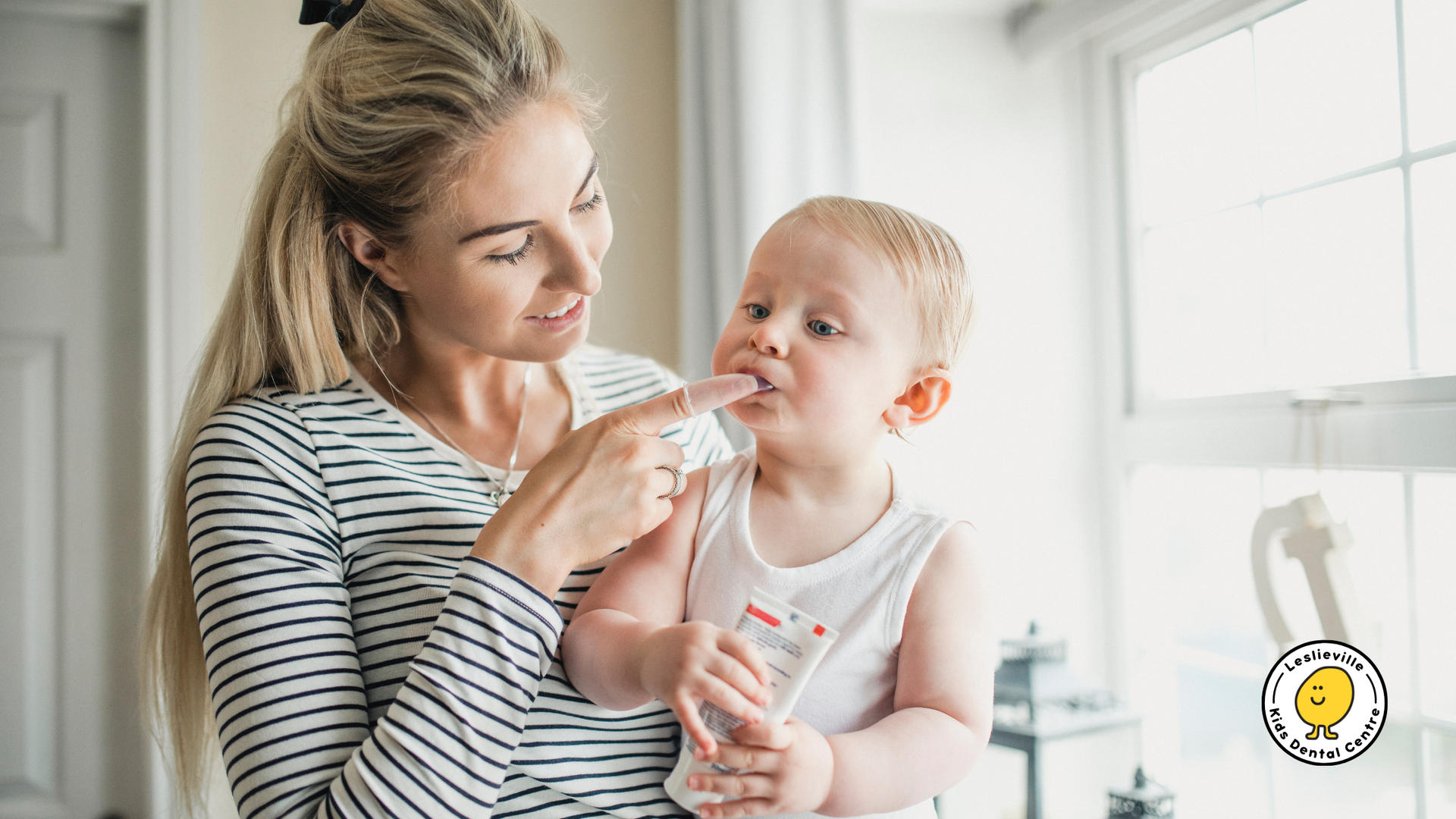 A woman is brushing her baby 's teeth with a toothbrush.