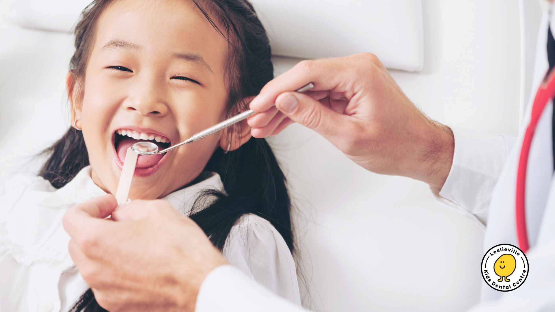 A little girl is getting her teeth examined by a dentist.