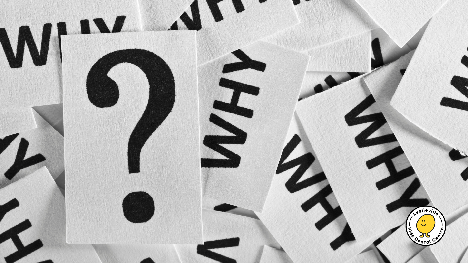 Large black question mark on white paper, surrounded by scattered