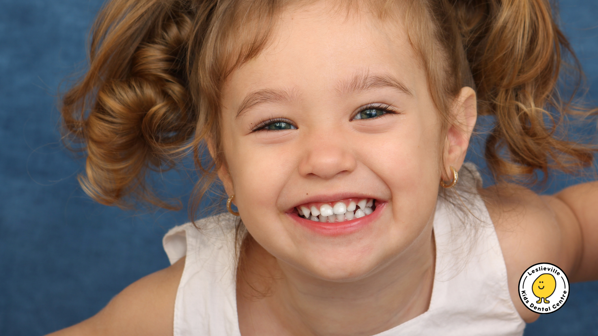 A little girl with braces on her teeth is smiling for the camera.