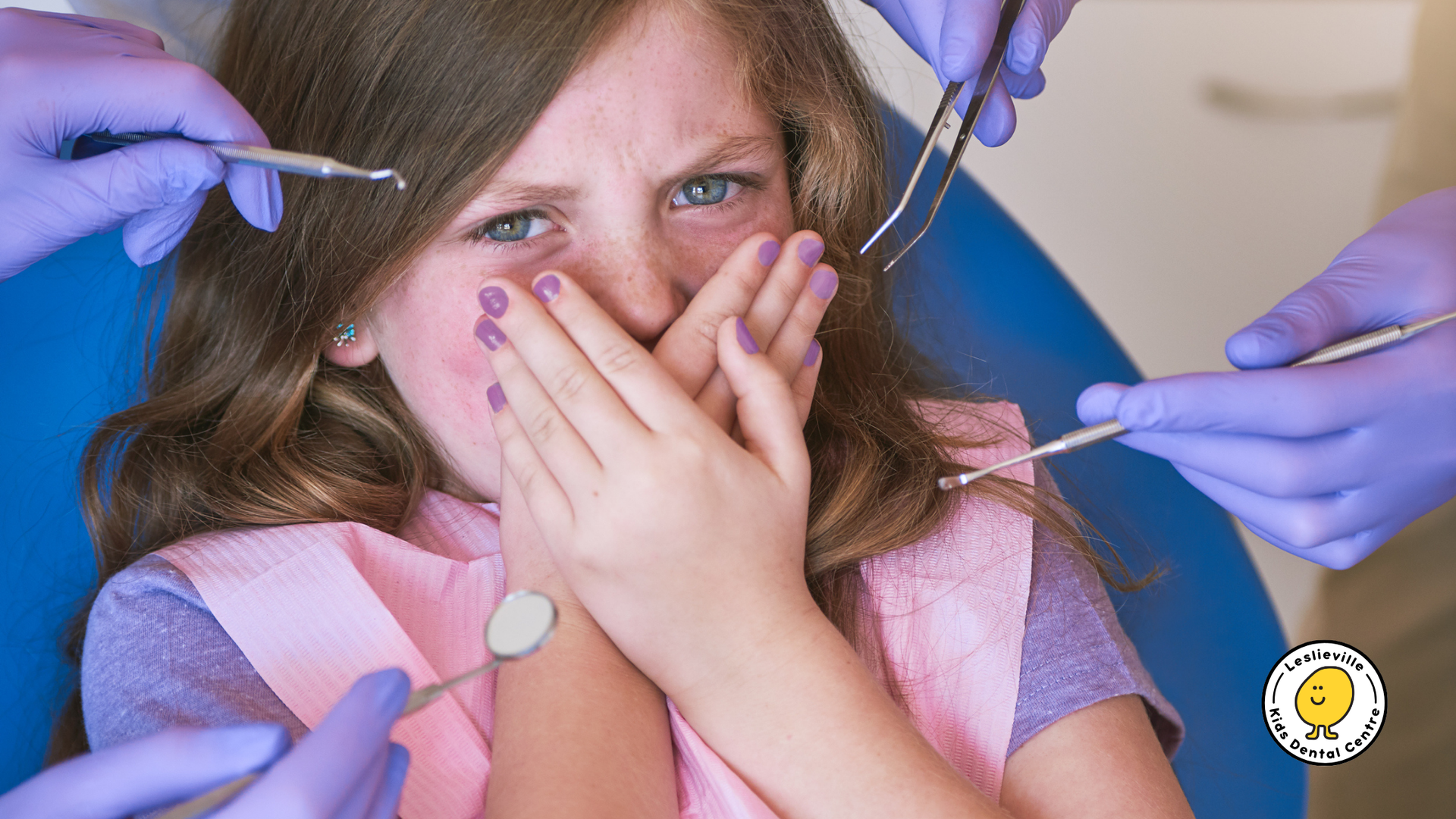 Girl with scared expression at dentist, hands covering mouth; dental tools and gloved hands visible.