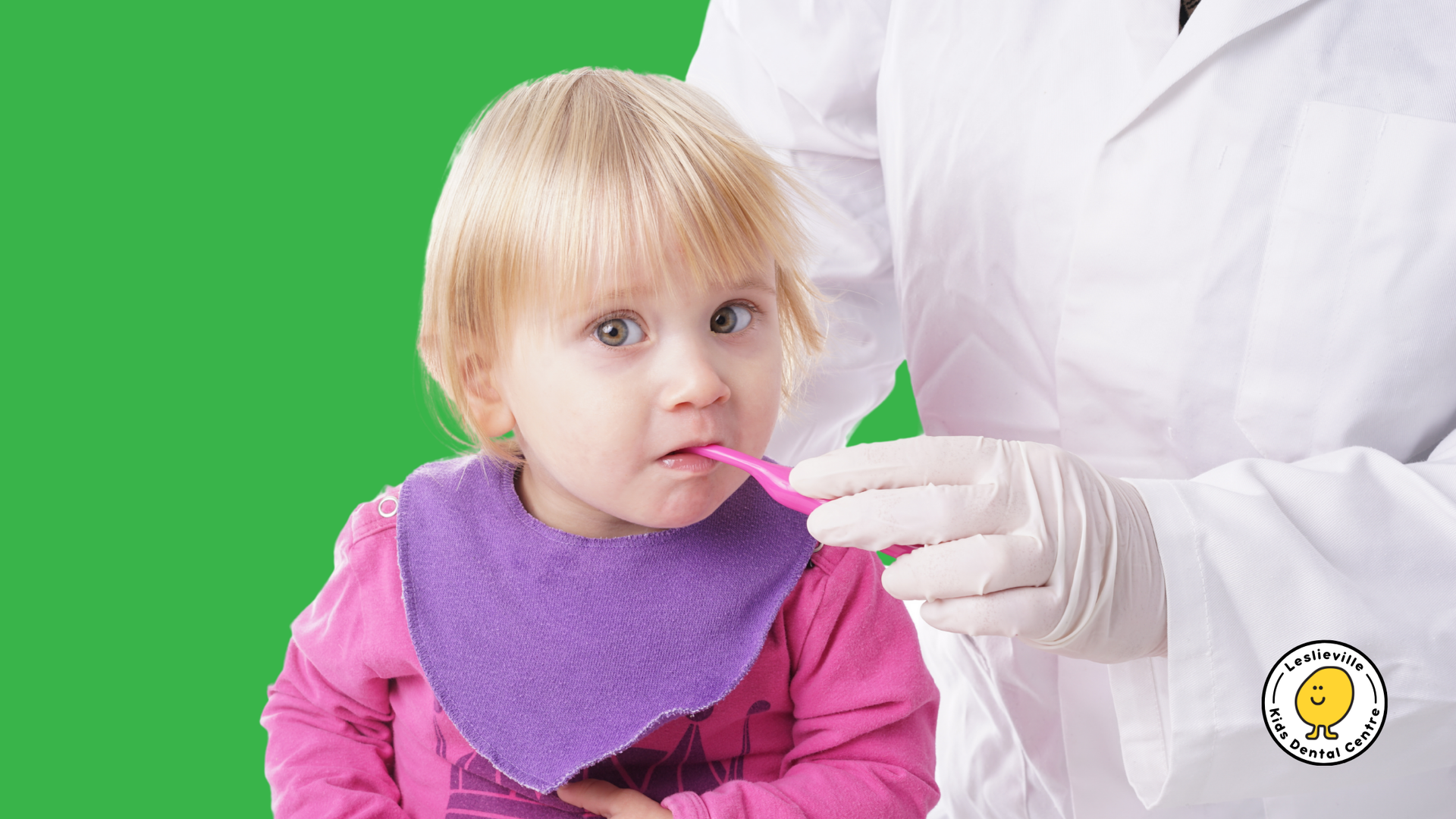 A little girl is brushing her teeth with a pink toothbrush.