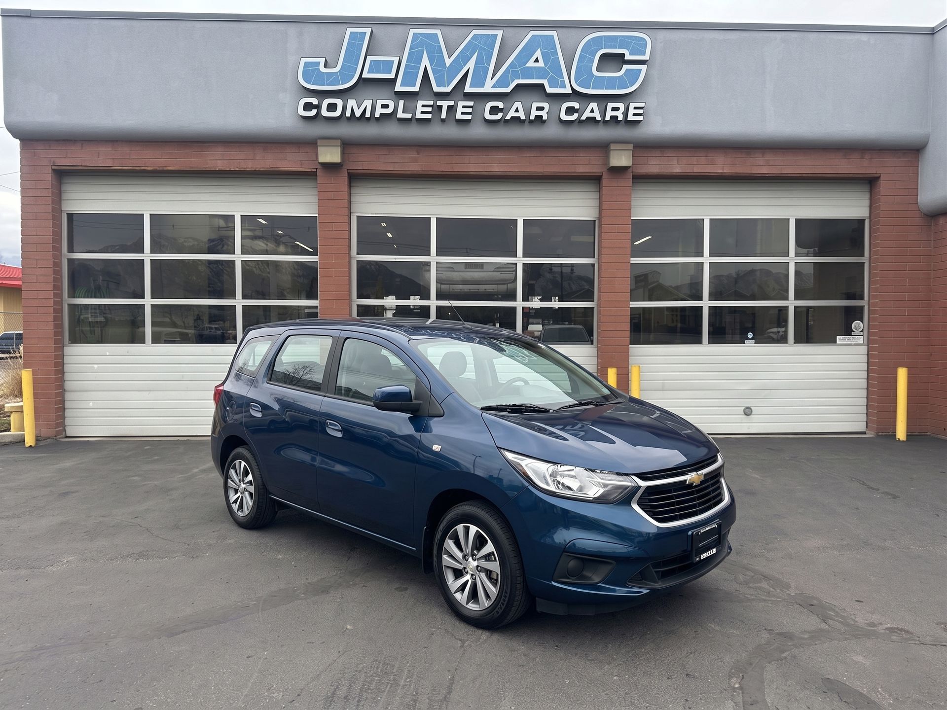 Blue minivan parked in front of J-MAC Complete Car Care auto shop