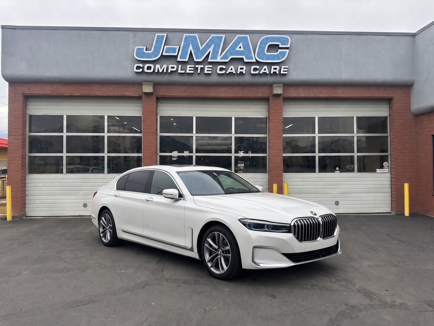 White BMW sedan parked outside J-MAC Complete Car Care garage
