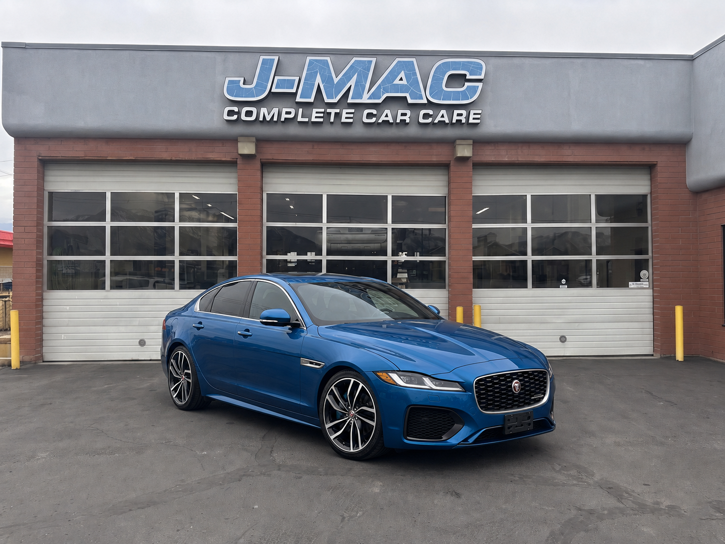 Blue sedan parked in front of J-MAC Complete Car Care garage