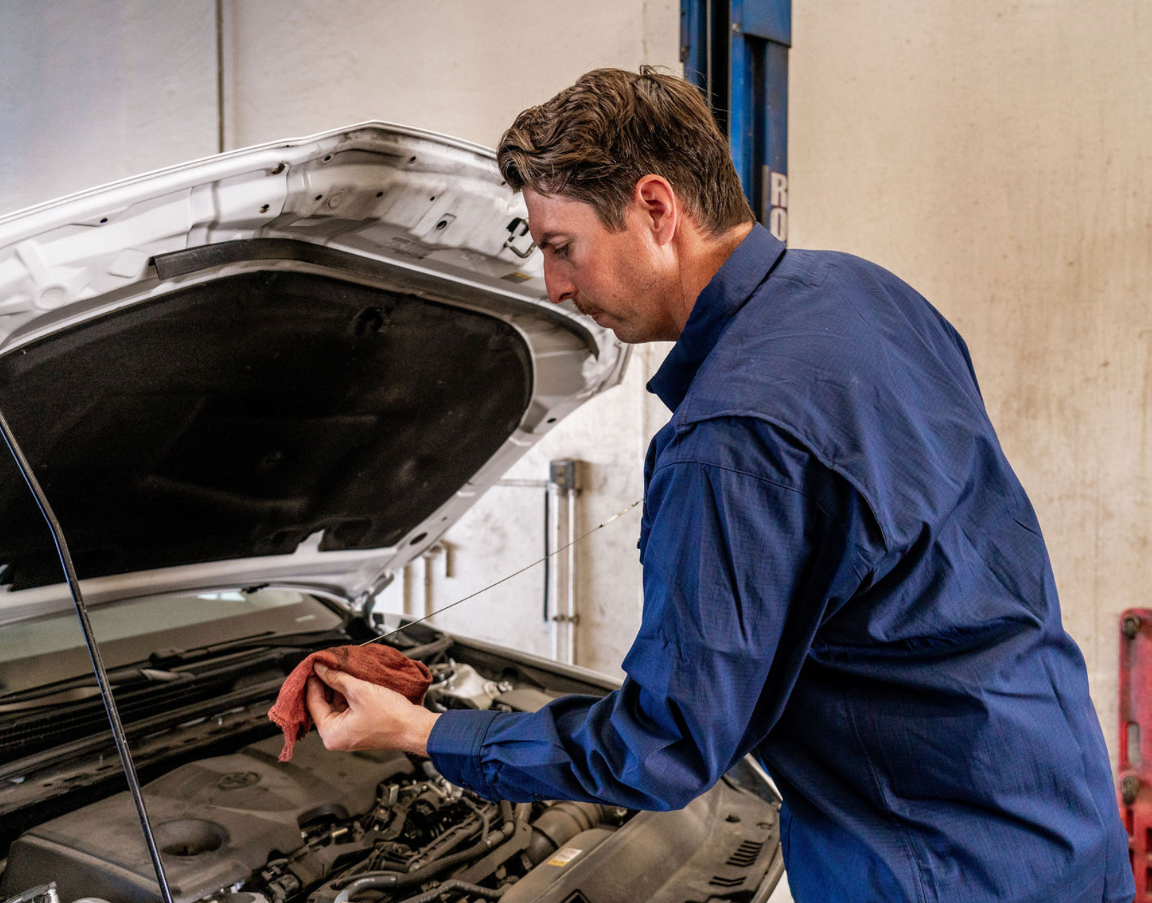 Mechanic inspecting a car engine in a garage with the hood open