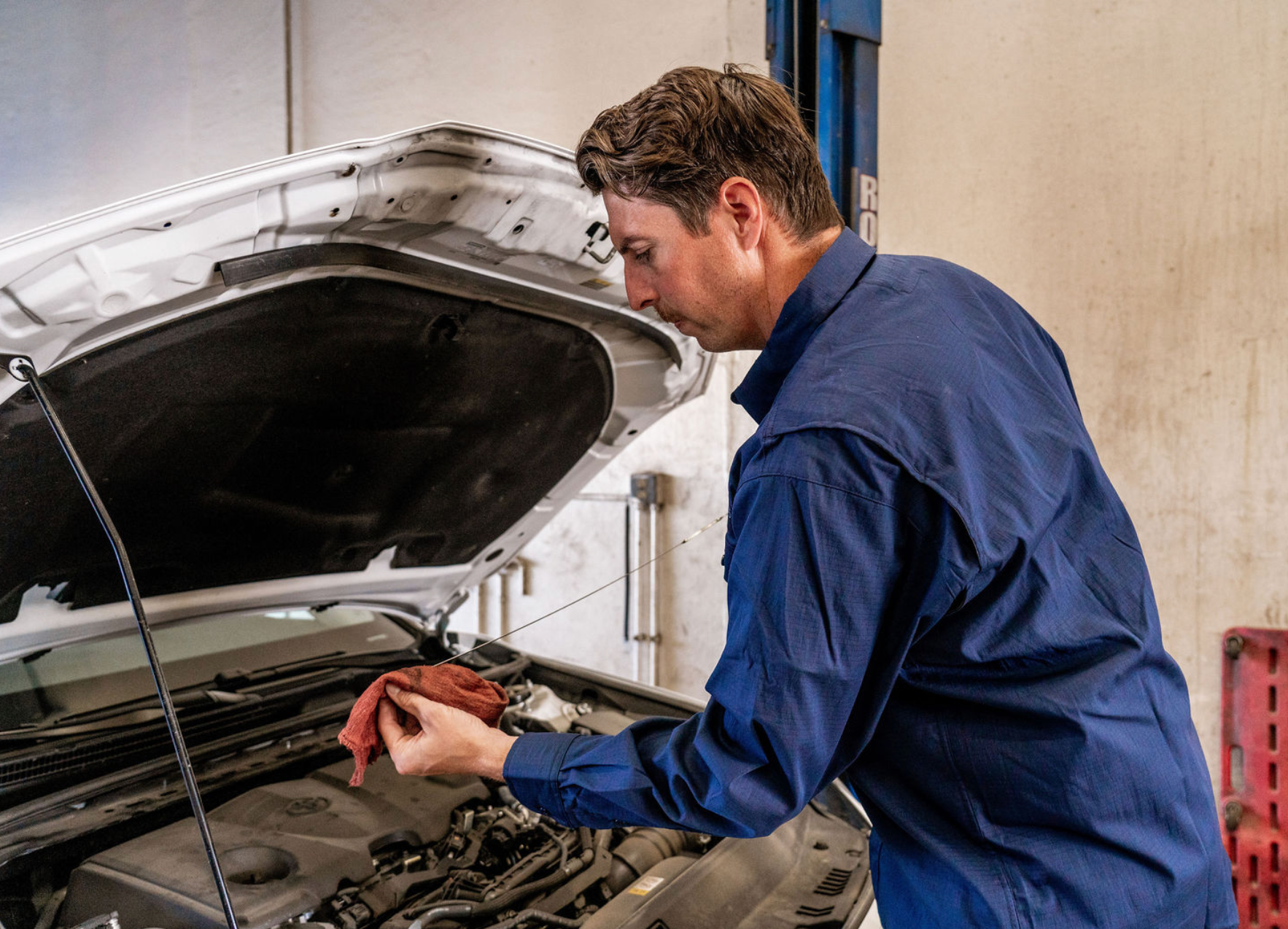 Mechanic inspecting a car engine with the hood open in a workshop