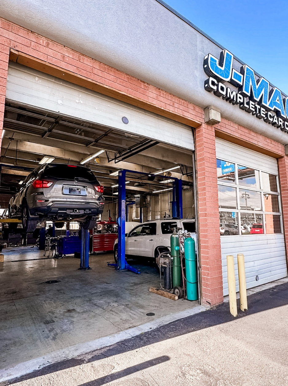 Auto repair shop with cars on lifts under a blue-and-white sign at the entrance