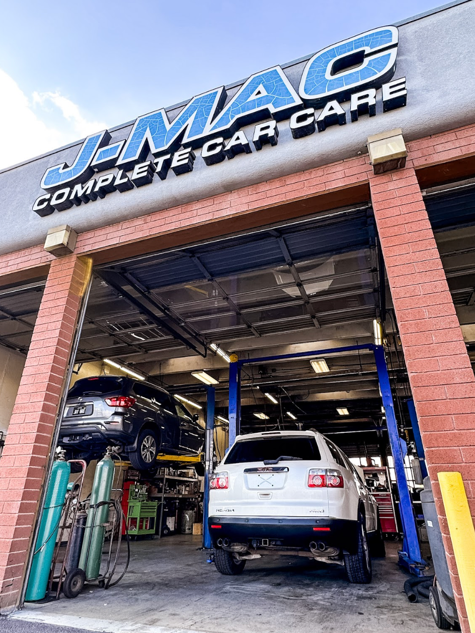 Auto repair shop with cars lifted inside, under a blue “MAC” sign at the entrance