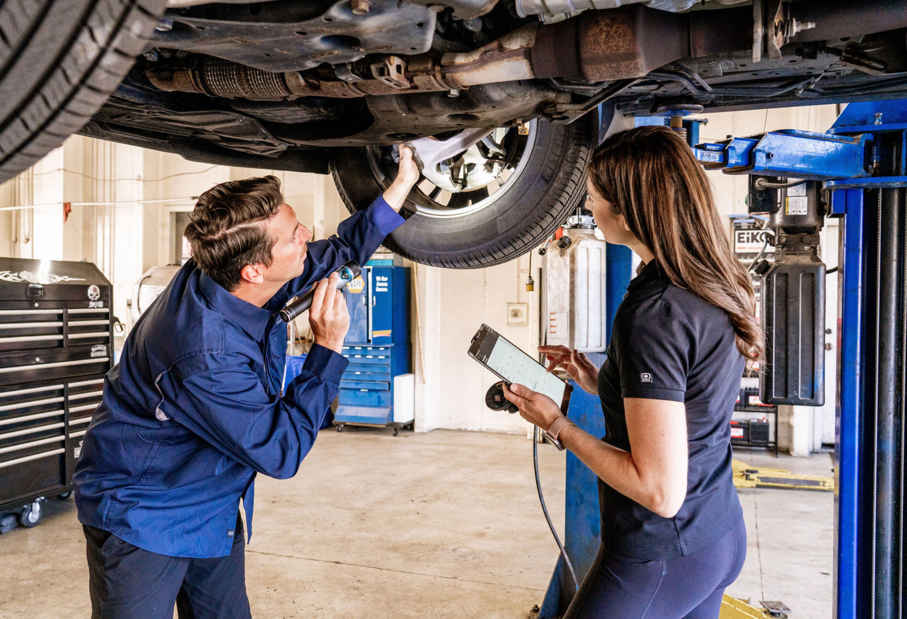 Mechanic and customer inspecting a car on a lift in an auto repair shop