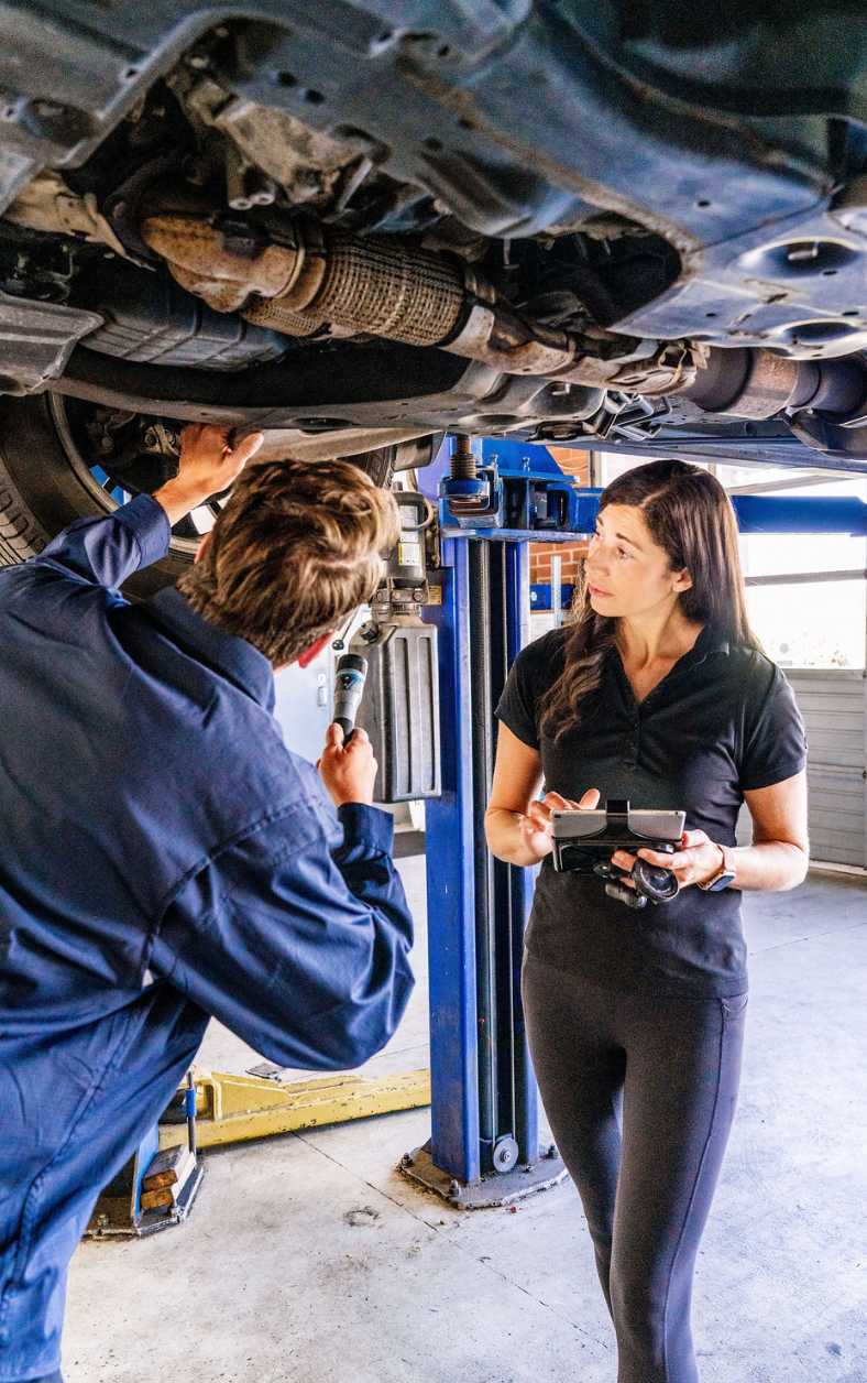 Mechanic and customer inspecting a car on a lift in an auto repair shop