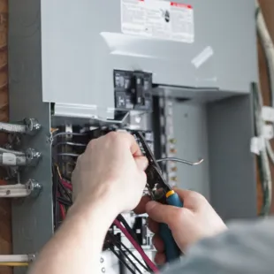 Horizon Electric USA - A person is working on an electrical box with a pair of pliers