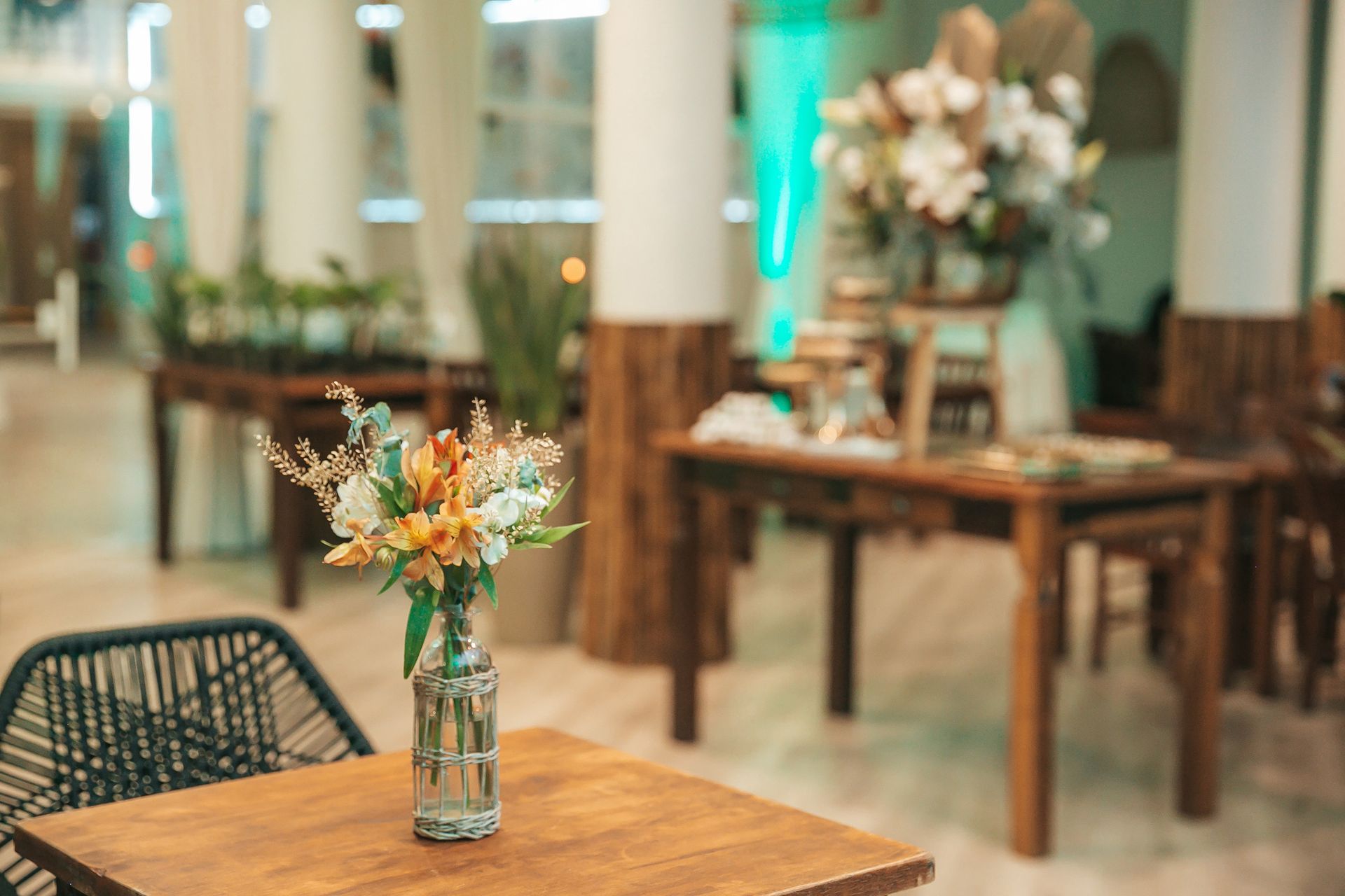 Arranjos florais sobre mesas de madeira em um café ou restaurante com iluminação suave.