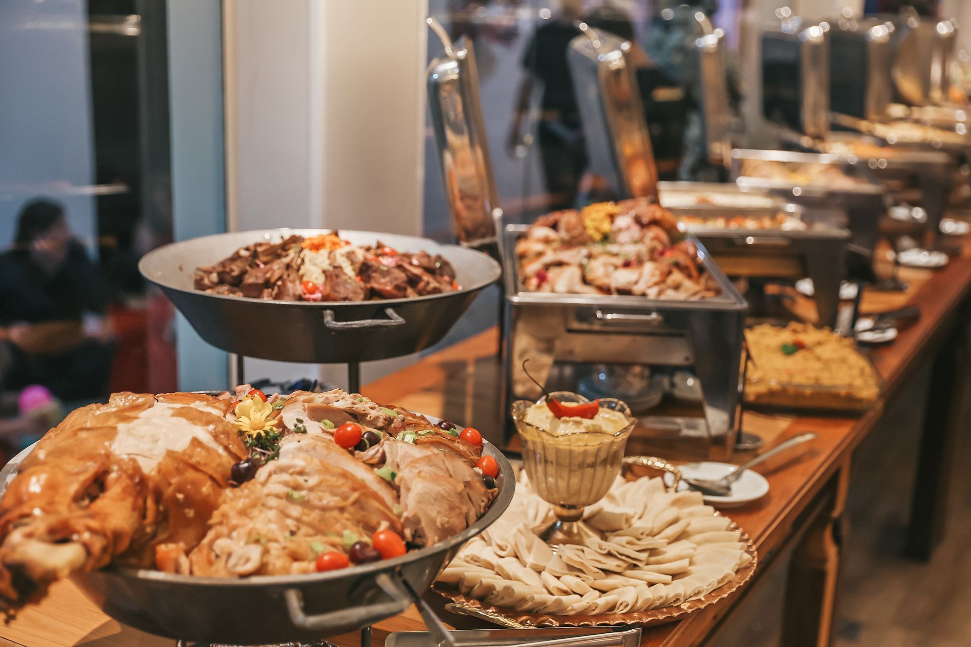 Mesa de buffet com pratos assados, saladas e aperitivos em um ambiente de restaurante aconchegante.