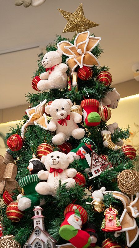 Árvore de Natal decorada com ursinhos de pelúcia, enfeites vermelhos e uma estrela dourada no topo.