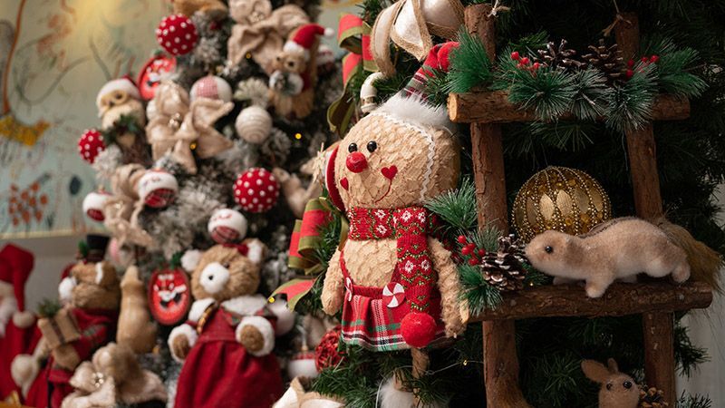 Decoração natalina festiva com ursinhos de pelúcia, um boneco do Papai Noel e enfeites vermelhos e verdes.