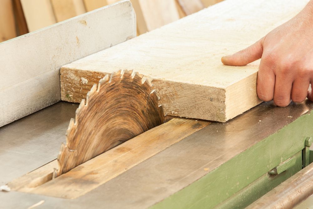 Hand Guiding Wood Through a Table Saw, Cutting a Plank in a Workshop — C K Carpentry in Byron Bay, NSW
