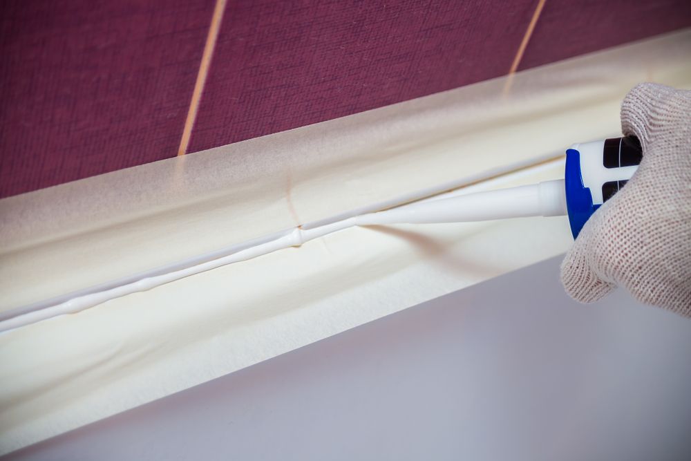 Gloved Hand Using a Blue-and-white Tool to Clean a White Fabric Seam — C K Carpentry in Byron Bay, NSW