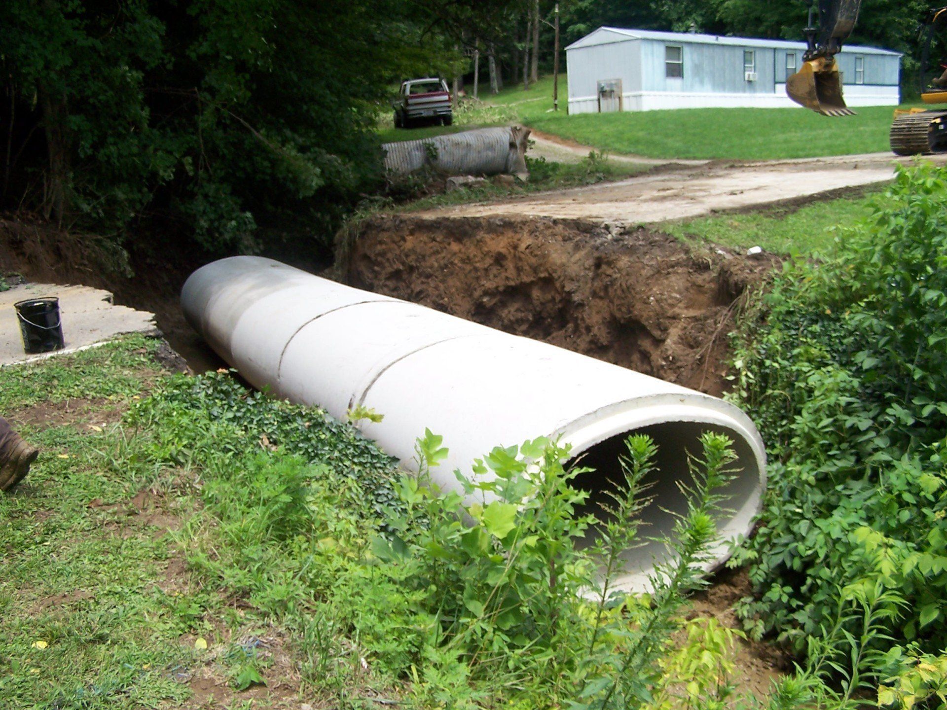 A large concrete pipe is being installed in a yard