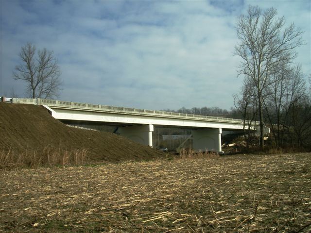 A bridge over a field with trees in the background