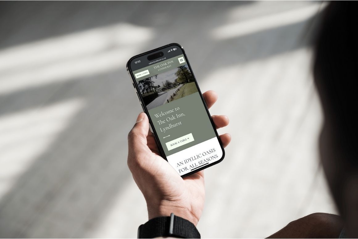 Hand holding a smartphone showing a website over a blurred indoor floor with sunlight and shadows