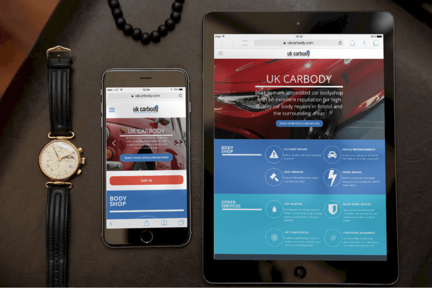 Smartwatch, smartphone, and tablet displaying a red-and-blue website on a dark tabletop